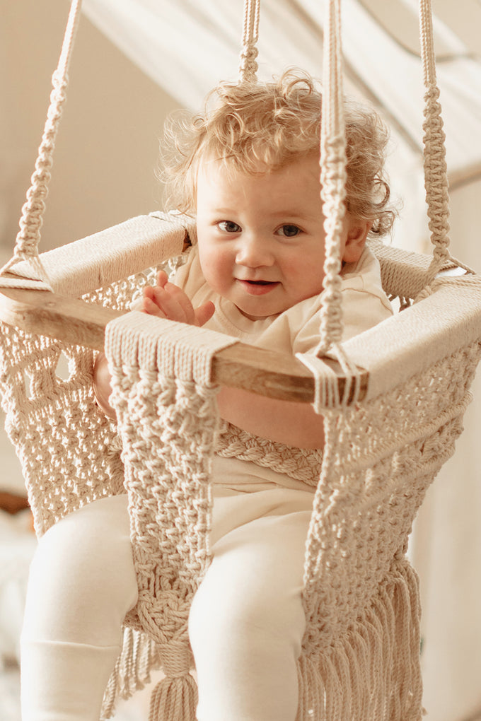 baby sitting in macrame baby swing